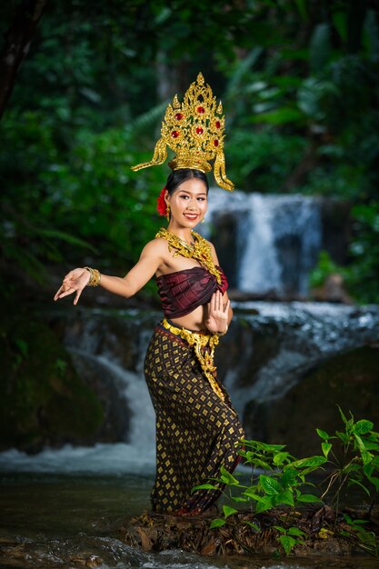 Een vrouw gekleed met een oude Thaise jurk bij de waterval.