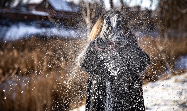 Een vrouw gooit sneeuw tijdens een wandeling bij zonnig weer in de winter