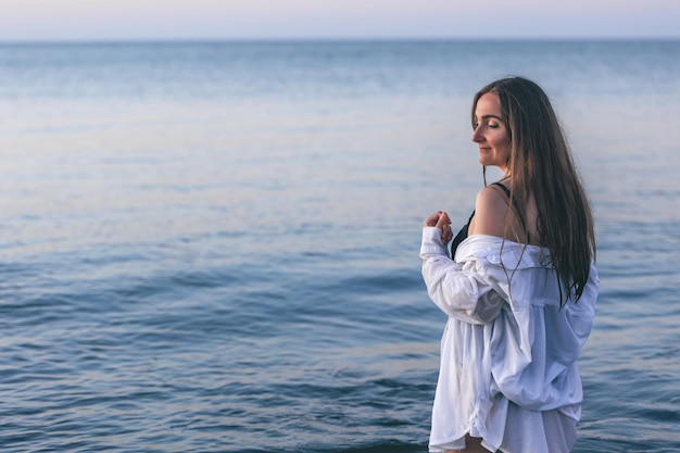 Een vrouw in een badpak en een wit overhemd in de zee