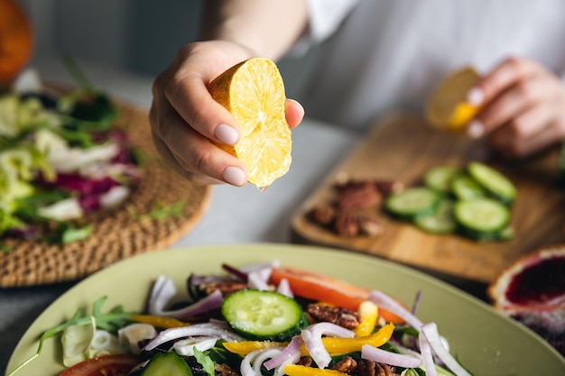 Gratis foto een vrouw maakt een salade van groenten en knijpt het sap van een citroenclose-up