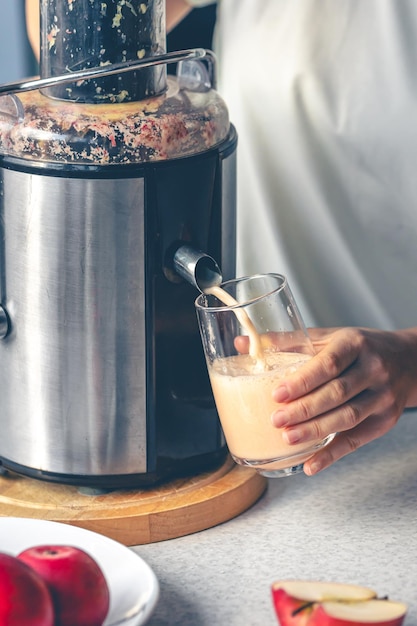 Een vrouw maakt thuis appelsap met een juicer