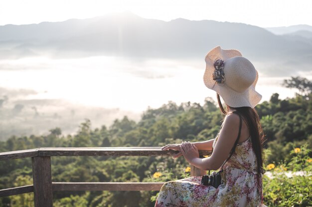 Een vrouw met een camera om het uitzicht op de bergen te bekijken