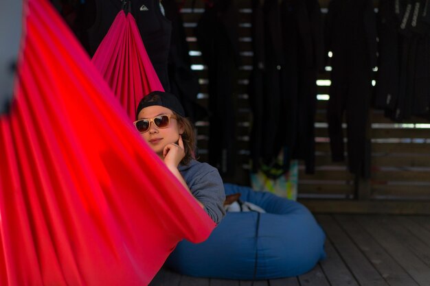 Een vrouw met zonnebril ligt in een rode hangmat