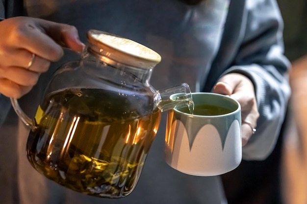 Gratis foto een vrouw schenkt 's avonds laat thee in een kopje