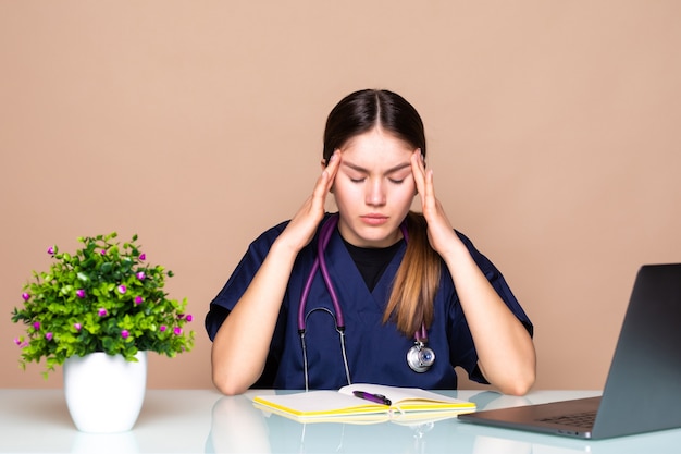 Een vrouwelijke arts in uniform werkt met een laptop cumulatieve stress, onwerk en stress veroorzaakt door het coronavirus dat zich over de hele wereld verspreidde