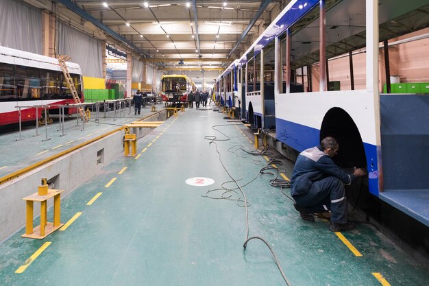 Een werkdag van moderne automatische busproductie met onafgewerkte autoarbeiders in beschermende uniforme auto-assemblagelijn voor auto's