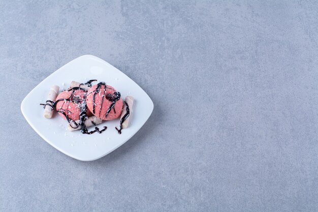 Een wit bord heerlijke roze donuts met hagelslag en zoete stokjes.