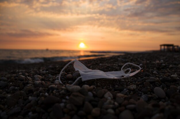 Een wit chirurgisch masker op een rotsstrand vuilnis achtergelaten op een strand in turkije in 2020 zonsondergang en zee