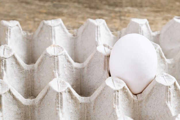 Een wit ei in het pak op houten achtergrond.