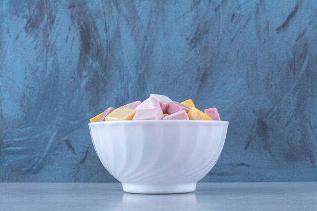 Een witte kom met roze en gele zoete zoetwaren Pastila
