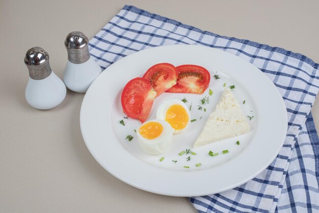 Een witte plaat van gesneden tomaat en gekookt ei.