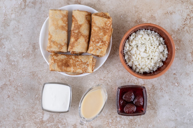 Een witte plaat van lekkere pannenkoeken en aardbeienjam