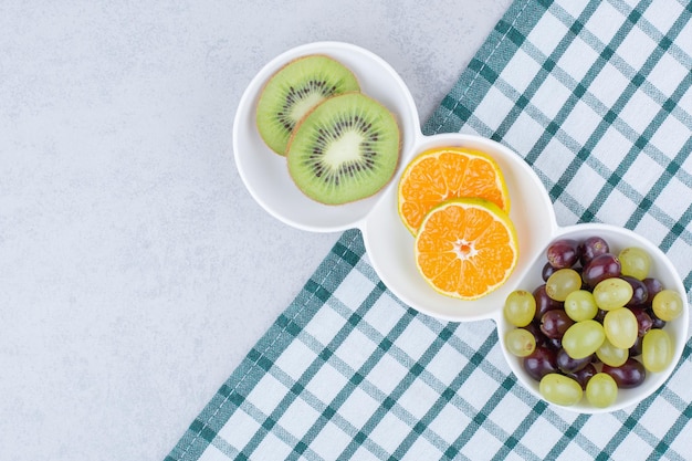 Een witte platen van vers fruit op tafelkleed. Hoge kwaliteit foto