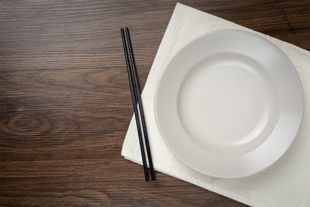 Een witte ronde lege platen en eetstokje op houten tafel