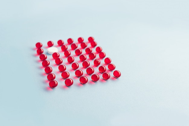 Een witte ronde tablet in een raster van rode capsules