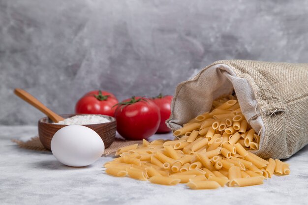 Een zak vol gedroogde italiaanse penne pasta met rode tomaten en bloem