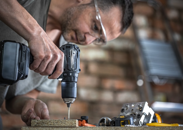 Een zelftappende schroef in een metalen bevestigingsgat op een houten strip schroeven met een schroevendraaier, het werk van een timmerman.