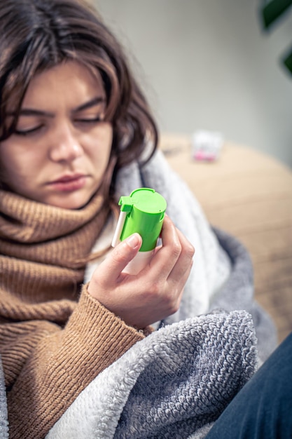 Een zieke jonge vrouw die hoestspray gebruikt