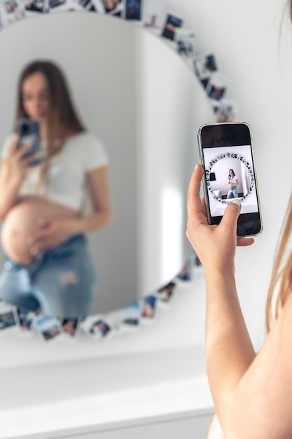 Een zwangere vrouw neemt een selfie in de spiegel het concept van het verwachten van een baby