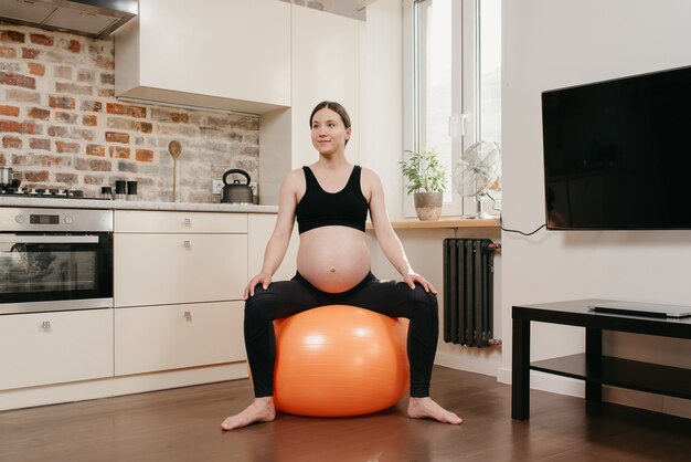 Een zwangere vrouw zit op een oefenbal en ontspant na de training