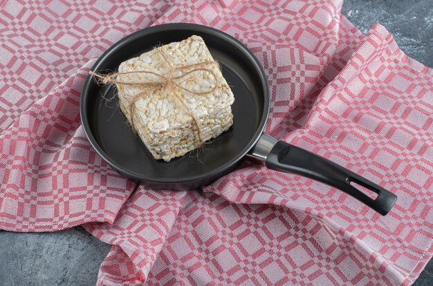 Een zwarte pan vol gepofte rijstbrood op een tafelkleed.