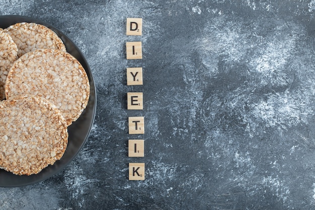 Een zwarte plaat vol gepofte rijstbrood op een marmeren ondergrond.