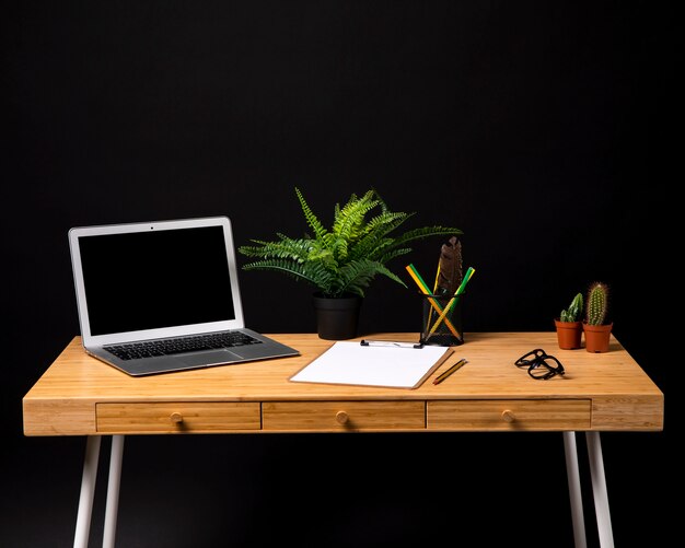 Eenvoudig houten bureau met klembord en laptop