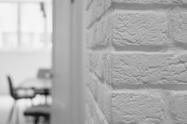 Eenvoudig kamerinterieur met witte bakstenen muur en meubels op de achtergrond van de wazige kamer, studio-ontwerpidee in loftstijl, minimalistisch design, redelijke eenvoud van interieurs