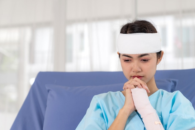Eenzame de verwondingsvrouw van ongevallenpatiënten op het bed van de Patiënt in het ziekenhuis wil naar huis gaan - medisch concept