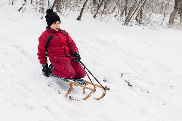 Eenzame jongen die van slee genieten die in de winter berijden