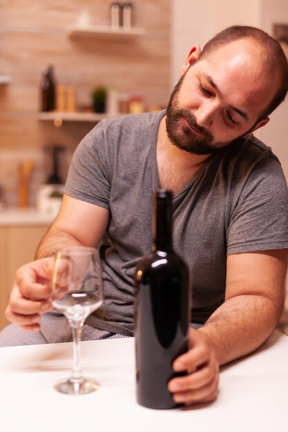 Eenzame man die naar een leeg glas wijn kijkt en teleurgesteld is?