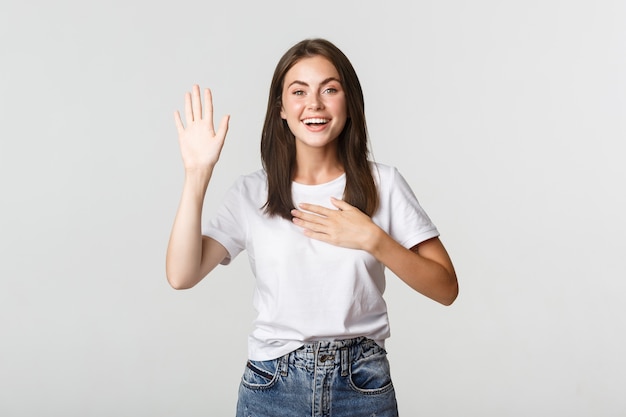 Eerlijk glimlachend schattig meisje vertelt de waarheid, hand opsteken om belofte te doen.