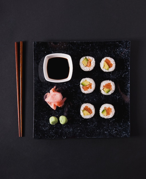 Eetstokjes dichtbij plaat met sushi en specerijen