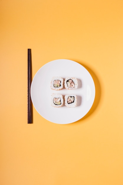 Eetstokjes dichtbij plaat met sushi