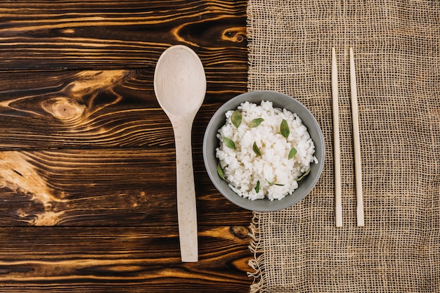 Eetstokjes en lepel in de buurt van gekookte rijst