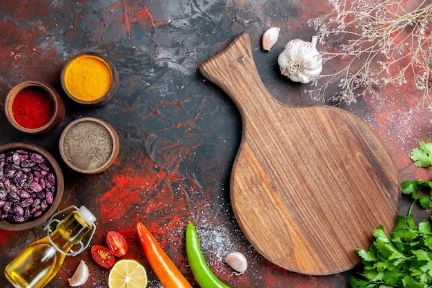 Eettafel gevallen olie fles bonen snijplank en verschillende kruiden op gemengde kleurentafel