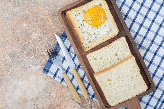 Ei-toast met kruiden op een houten bord met bestek