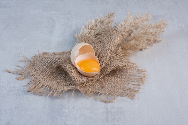 Eidooier in een gebroken schaal op een stuk doek op marmeren tafel.