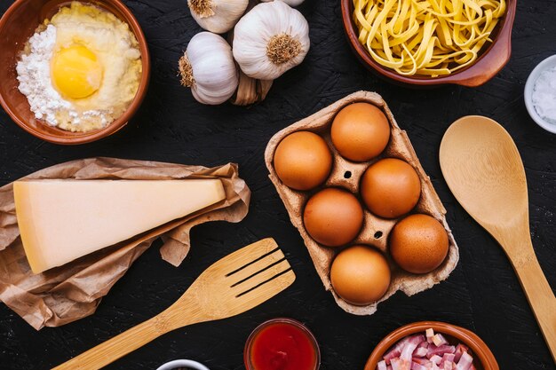 Eieren en kaas te midden van pasta-ingrediënten en keukengerei