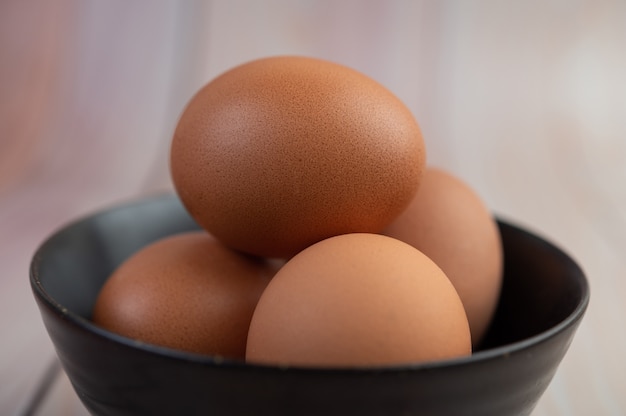 Eieren geplaatst in een kopje op een houten vloer.