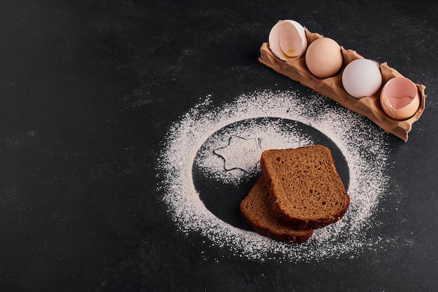 Eierschalen en sneetjes brood op zwarte ondergrond.