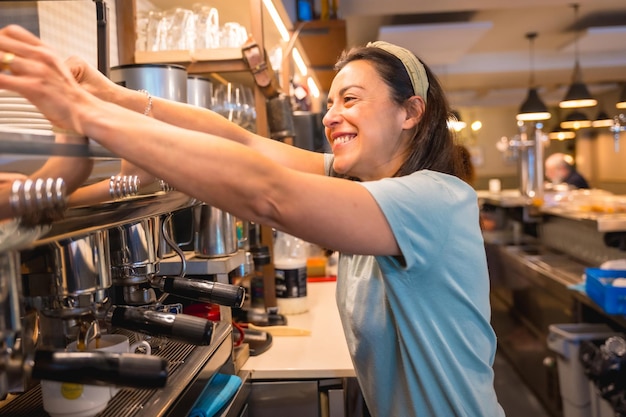 Eigenaar van de vrouwelijke cafetaria die koffie bereidt in een koffiezetapparaat de beperkingen als gevolg van covid
