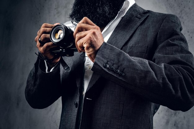 Elegante bebaarde professionele fotograaf in een pak fotograferen met een compacte DSLR-camera.