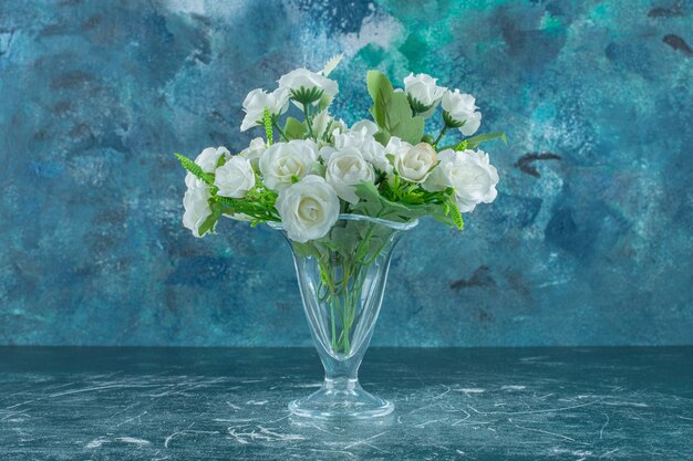 Elegante bloemen in een glazen kan, op de witte tafel.