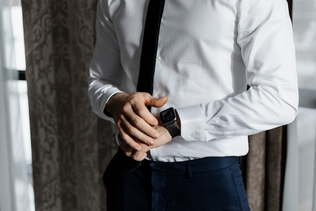 Elegante man gekleed in een wit overhemd en een stropdas met een slimme horloge