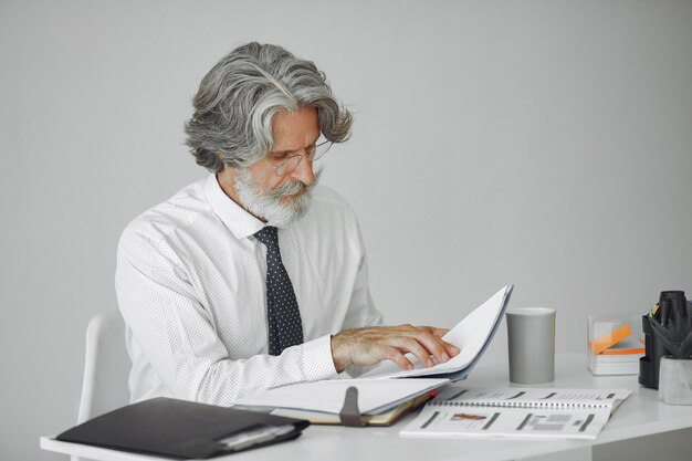 Elegante man in kantoor. Zakenman in wit overhemd. Man werkt met documenten.