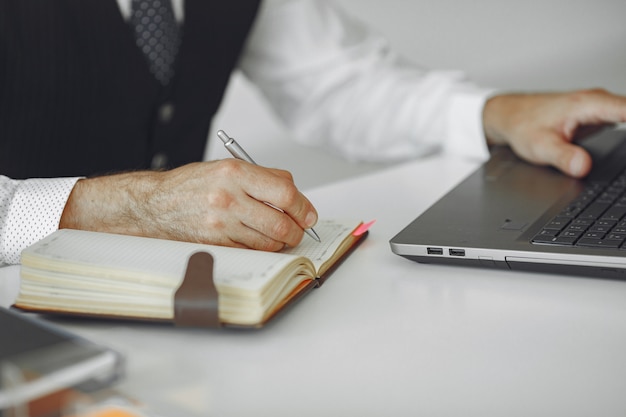 Elegante man in kantoor. zakenman in wit overhemd. man werkt met laptop.