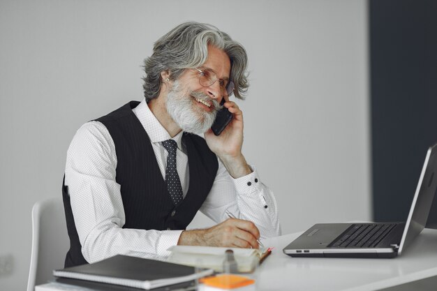 Elegante man in kantoor. Zakenman in wit overhemd. Man werkt met telefoon.