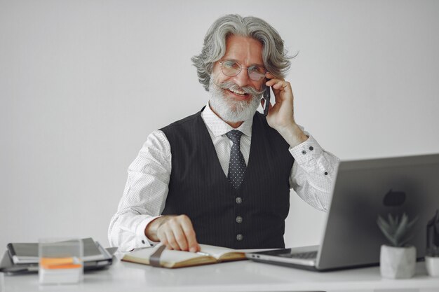 Elegante man in kantoor. Zakenman in wit overhemd. Man werkt met telefoon.