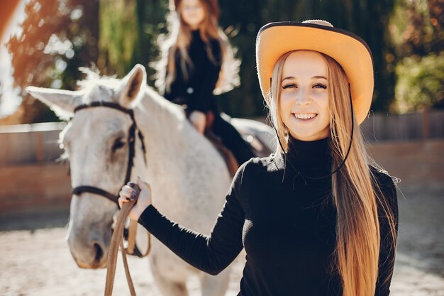 Elegante meisjes met een paard in een boerderij